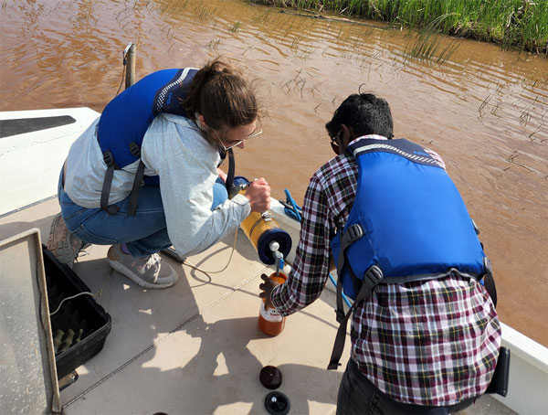a man and a woman on a boat getting water samples from a river