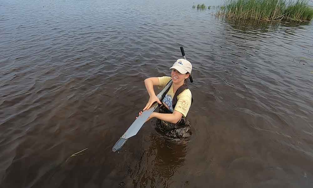 A young woman using a piece of equipment in waist deep water