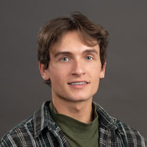 A young man with brown hair wearing a dark button up shirt