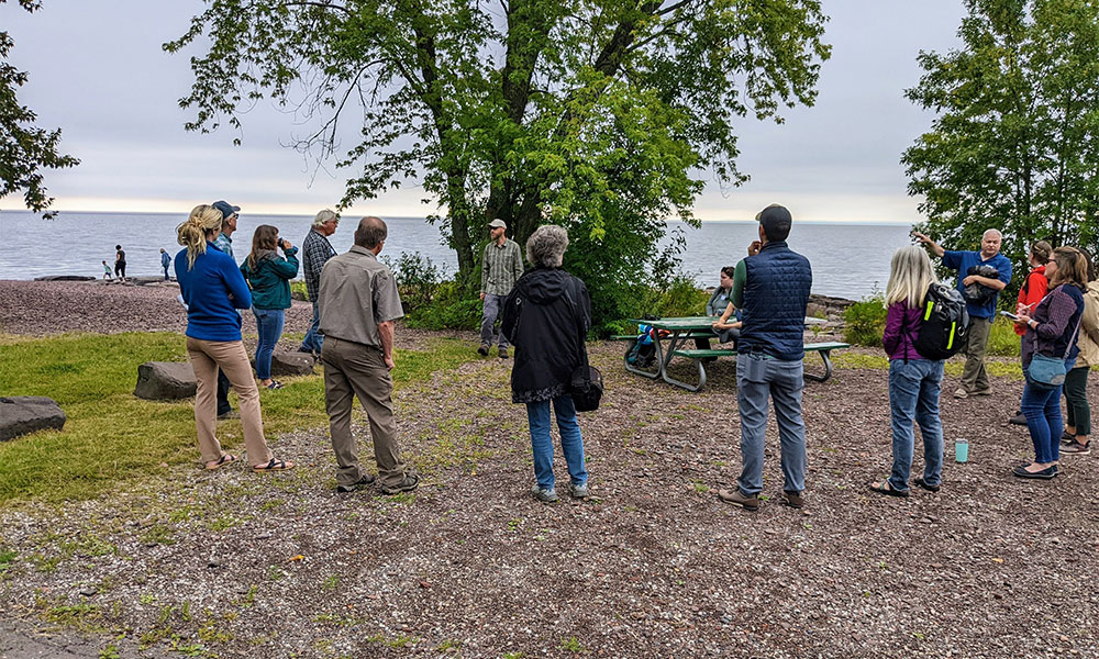 A small group of people having a meeting on a lake shoreline