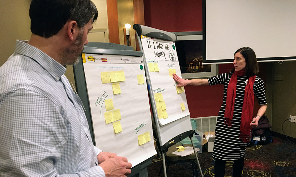 A woman talking to a man about a topic laid out on two large white pads of paper