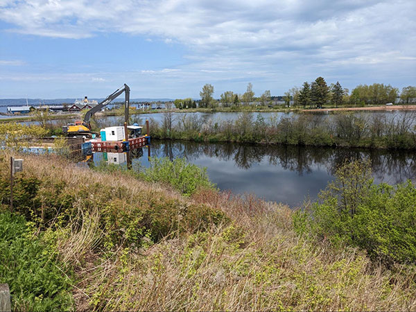 A small pond being worked on with a large excavator.